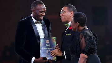 Usain Bolt recibe un premio de manos del primer ministro jamaicano, Andrew Holness y de la ministra de Cultura y Deporte, Olivia Grange.