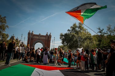 Decenas de manifestantes extienden una bandera de Palestina durante una manifestación en apoyo a Palestina.