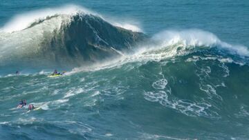 Dos olas gigantes en forma de A, una tras otra, a punto de romper en la Praia do Norte de Nazaré (Portugal), con varios surfistas viéndolo desde sus jet ski, el 10 de noviembre del 2023.