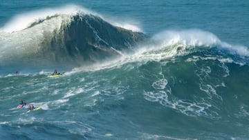 Dos olas gigantes en forma de A, una tras otra, a punto de romper en la Praia do Norte de Nazaré (Portugal), con varios surfistas viéndolo desde sus jet ski, el 10 de noviembre del 2023.