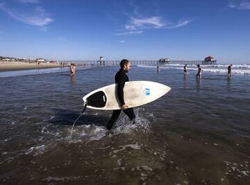 Huntington Beach (California, Estados Unidos) este fin de semana, con un surfista metiéndose en el agua en plena pandemia. Las playas han reabierto -con restricciones- pero se sigue recomendando que la gente se quede en casa.