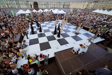 Los ajedrecistas Alexander Khalifman (derecha) y Maxim Matlakov juegan una partida de ajedrez mientras actores, vestidos como piezas, reproducen sus movimientos en un enorme tablero durante la celebración del Día Internacional del Ajedrez, que tiene lugar el 20 de julio, en la Plaza Dvortsovaya de San Petersburgo, Rusia. 