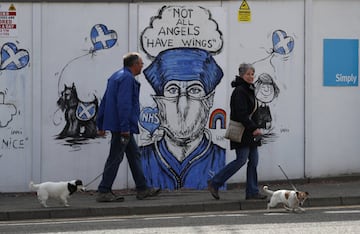 People are seen walking their dogs while passing a graffiti in support of the NHS, as the spread of the coronavirus disease (COVID-19) continues, Perth, Scotland, Britain, April 27, 2020. REUTERS/Russell Cheyne