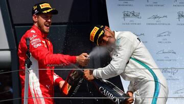 Ferrari's German driver Sebastian Vettel (L) celebrates winning the British Formula One Grand Prix with second-placed Mercedes' British driver Lewis Hamilton on the podium after the British Formula One Grand Prix at the Silverstone motor racing circuit in Silverstone, central England, on July 8, 2018. / AFP PHOTO / Andrej ISAKOVIC