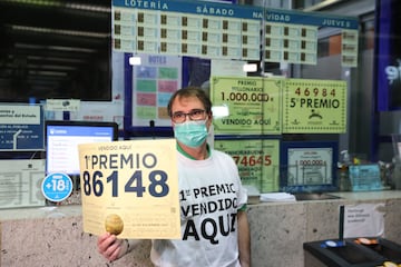 Javier Muñoz, empleado de la administración de Lotería en la estación del AVE de Atocha. El lotero muestra el numero del  primer premio, cuya administración vendió 129 series de este número.