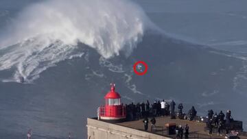 El surfista CJ Macias surfeando una ola gigante en el pico Big Mama de Praia do Norte (Nazaré, Portugal) durante el swell XXL del 8 de enero del 2022, con gente mirándolo desde el faro y el labio de la ola a punto de caer sobre él para provocarle un terrible wipeout que le rompería el brazo.