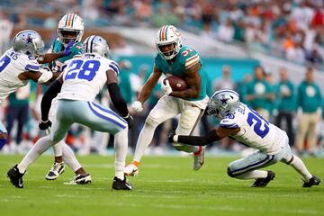 Raheem Mostert of the Dolphins is tackled by DaRon Bland.