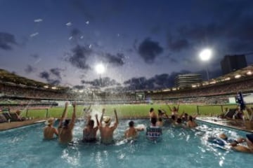 Aficionados australianos se divierten en una piscina situada en la grada del Brisbane Cricket Ground, popularmente conocido como The Gabba, mientras se juega el partido de cricket entre Australia y Pakistán. AFP PHOTO / Saeed Khan