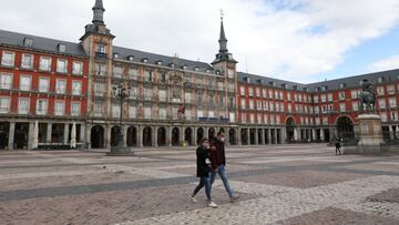 People wearing face covering walk through a deserted Plaza Mayor square, Friday October 2, 2020.
