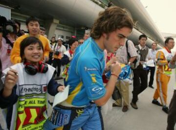 Renault's world champion Formula One driver Fernando Alonso of Spain runs away from Chinese fans asking for autographs after taking part in the fourth practice session for the Chinese Grand Prix in Shanghai October 15, 2005. REUTERS/Bobby Yip