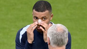 France's forward #10 Kylian Mbappe (L), wearing a band-aid after breaking his nose during his country's opening win against Austria, speaks with France's head coach Didier Deschamps during a training session within the UEFA Euro 2024 Football Championship, at the Home Deluxe Arena Stadium in Paderborn, western Germany, on June 19, 2024. Mbappe underwent tests at a hospital in Duesseldorf before rejoining the France squad at their base in Paderborn. (Photo by FRANCK FIFE / AFP)