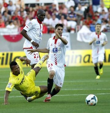 El centrocampista camerunés del Sevilla Stéphane M'Bia (c) y el defensa Coke Andújar (d) derriban al delantero nigeriano del Villarreal Ikechukwu Uche (i), durante el partido correspondiente a la trigésimo sexta jornada de Liga.