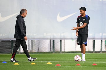 Barcelona's coach Hansi Flick (L) and Barcelona's Spanish forward #19 Lamine Yamal talk during a training session on the eve of the Spanish league football match between Real Madrid CF and FC Barcelona at the Joan Gamper training ground in Sant Joan Despi, near Barcelona, on October 25, 2024. (Photo by Josep LAGO / AFP)