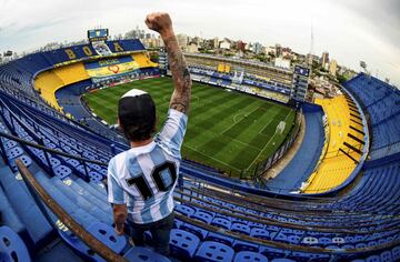 Un hincha con la camiseta de Argentina posa frente a una gran pancarta de homenaje a Maradona, en una panorámica de La Bombonera completamente vacía, antes del partido entre Boca Juniors y Newells Old Boys. Tras la muerte de la leyenda, el campeonato argentino ha sido rebautizado con el nombre Copa Diego Armando Maradona.