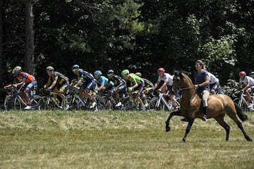 Un jinete cabalgando junto al pelotón de ciclistas durante la décimo etapa del Tour de Francia de 2017.