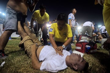 Personal de atención médica atiende a un hombre herido que yacía en la cancha luego de una estampida durante un partido de fútbol entre Alianza y FAS en el estadio Cuscatlán en San Salvador.