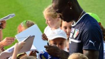 Balotelli firma aut&oacute;grafos a varios ni&ntilde;os tras un entrenamiento.