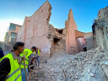 Vecinos trabajan para quitar los escombros junto a un edificio histórico en la ciudad de Marrakech.