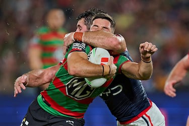 Hay abrazos que, más que reconfortar, resultan dolorosos. Especialmente si el que los da mide casi dos metros y pesa más de cien kilos. Peter Mamouzelos, de los Rabbitohs, puede dar fe de ello. En la imagen, es placado durante el partido de la quinta ronda de la NRL entre South Sydney Rabbitohs y Sydney Roosters en el Estadio Accor,  en Sídney (Australia). 