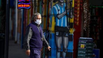 A man wearing a face mask as a preventive measure against the coronavirus disease (COVID-19) walks past a grocery store painted with a graffiti depicting Diego Maradona, after CONMEBOL announced Argentina pulled out hosting the Copa America, in Buenos Aires, Argentina May 31, 2021. REUTERS/Agustin Marcarian