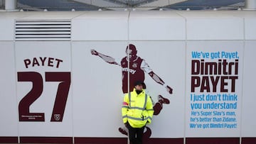 A security guard stands beside the club mural praising West Ham United's French midfielder Dimitri Payet ahead of the English Premier League football match between West Ham United and Crystal Palace