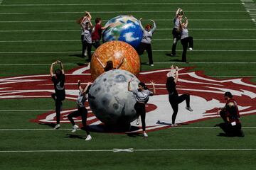 La gente baila junto a representaciones de la tierra, el sol y la luna en el estadio Saluki, antes de un eclipse solar, donde la luna tapará el sol, en Carbondale, Illinois.