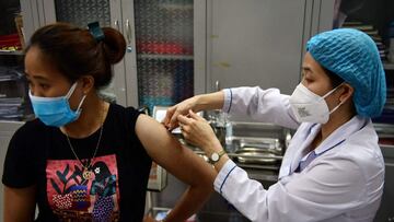 A woman receives the Moderna Covid-19 coronavirus vaccine at a primary school in Hanoi on July 27, 2021. (Photo by NHAC NGUYEN / AFP)