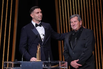 El portero del Aston Villa, Emiliano Martínez, recibe en el escenario el trofeo Yachine al mejor portero del mundo junto a su padre Alberto Martínez durante la ceremonia de entrega del Balón de Oro de Fútbol de Francia 2023