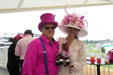 Los asistentes visten atuendos sofisticados, con sombreros extravagantes y trajes elegantes.