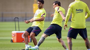BARCELONA, SPAIN - MAY 25: In this handout provided by FC Barcelona Luis Suarez (L) of FC Barcelona plays the ball with his teammate Lionel Messi (R) during a training session on May 25, 2020 in Barcelona, Spain. Spanish LaLiga clubs are back training in