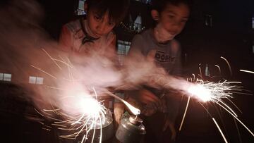KUALA LUMPUR, MALAYSIA - MAY 23: - Two Muslim boys light up a pair of firecrackers on the eve of Eid al-Fitr on May 23 2020 in Kuala Lumpur, Malaysia. Under the new normal, congegrations and visits are discouraged, and families have to celebrate one of t