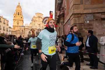 Varios participantes de la San Silvestre de la ciudad de Murcia 2024 pasan junto a la catedral.