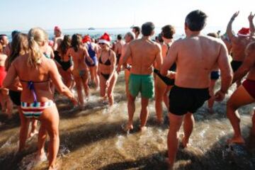 Decenas de ciudadanos participaron este mediodía en el tradicional primer baño del año en la playa de Sant Sebastià del barcelonés barrio de la Barceloneta.