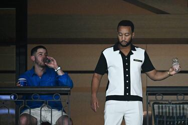 Los cantantes Nick Jonas y John Legend esperan en sus palcos durante la clasificación de los ejercicios por equipos de gimnasia artística en el Bercy Arena de París.