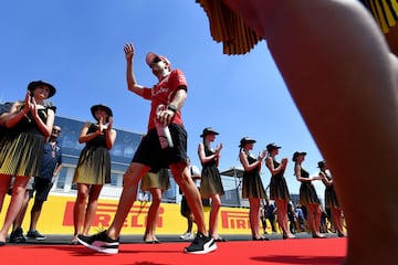 Sebastian Vettel saluda mientras pasa por delante de las chicas de la parrilla.