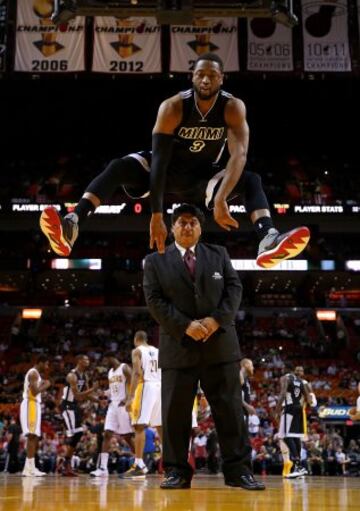 Dwyane Wade de los Miami Heat salta sobre una persona de seguridad.