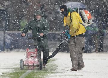 Operarios del club italiano retiran la nieve de las lineas del terreno de juego.