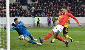 Switzerland's forward Haris Seferovic (R) scores his team's second goal past Belgium's goalkeeper Thibaut Courtois