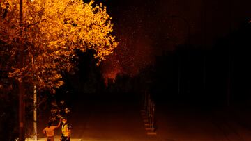People stand as sparks fly in the bacground during a wildfire in Tres Cantos, near Madrid, Spain, August 11, 2025. REUTERS/Juan Medina TPX IMAGES OF THE DAY