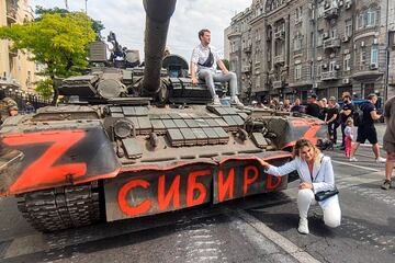 En esta foto tomada de un video, una mujer posa para una foto en un vehículo blindado ruso, que dice "Siberia", estacionado en una calle de Rostov. 