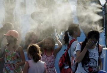 Varios aficionados se refresca delante de un ventilador en el Abierto de 2014 de Australia en Melbourne