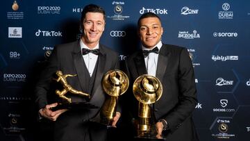 This handout picture made available by the Dubai Globe Soccer Awards on December 27, 2021 shows (L to R) Polish footballer Robert Lewandowski posing for a photo with his awards "Maradona Award for Best Goal Scorer of the Yea" and the "TikTok Fans Player of the Year"; alongside French footballer Kylian Mbappe, winner of the "Best Men's Player of the Year" award during the 2021 Globe Soccer Awards at the Burj Khalifa in the gulf emirate. (Photo by Elmer MAGALLANES / Dubai Globe Soccer Awards / AFP) / === RESTRICTED TO EDITORIAL USE - MANDATORY CREDIT "AFP PHOTO / HO / Dubai Globe Soccer Awards" - NO MARKETING NO ADVERTISING CAMPAIGNS - DISTRIBUTED AS A SERVICE TO CLIENTS ===