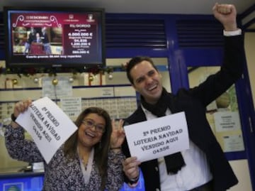 Marcos Delgado, dueño de la administración de lotería ubicada en la calle Condesa de Venadito en Madrid, acompañado de la vendedora Jenyffer Hoyos celebran su el segundo premio del Sorteo Extraordinario de la Lotería de Navidad que ha recaído en el 04536, vendido en parte en esta administración. 