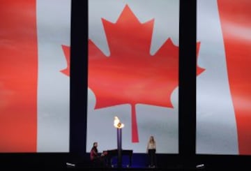 The torch is seen infront of a Canadian national flag as Artists perform during the opening ceremony for the 2015 Pan American Games at the Rogers Centre in Toronto, Ontario, on July 10, 2015.    AFP PHOTO / HECTOR RETAMAL