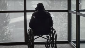 Kai Jones en silla de ruedas mirando cómo nieva por una ventana.