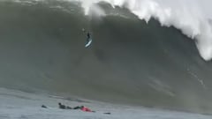 Grant &#039;Twiggy&#039; Baker literalmente volando con su tabla de surf azul en una ola gigante en Mavericks mientras otros surfistas se lo miran remando por el lado de esta ola de California, en enero del 2021. 