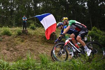 Davide Ballerini y Sonny Colbrelli animados por un aficionado que sostiene una bandera de Francia en alto.