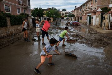 Carmen Palomino y sus hijos Mario, de 8 años, y Alex, de 6, quitan barro mientras ayudan a los vecinos después de las fuertes lluvias en Villamanta, España.