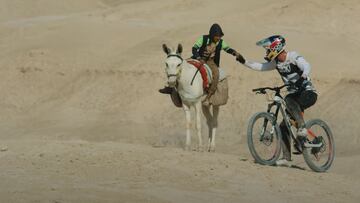 El piloto de MTB Fabio Wibmer chocando la mano con un tipo que va en caballo en el desierto de Israel. 