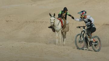 El piloto de MTB Fabio Wibmer chocando la mano con un tipo que va en caballo en el desierto de Israel.